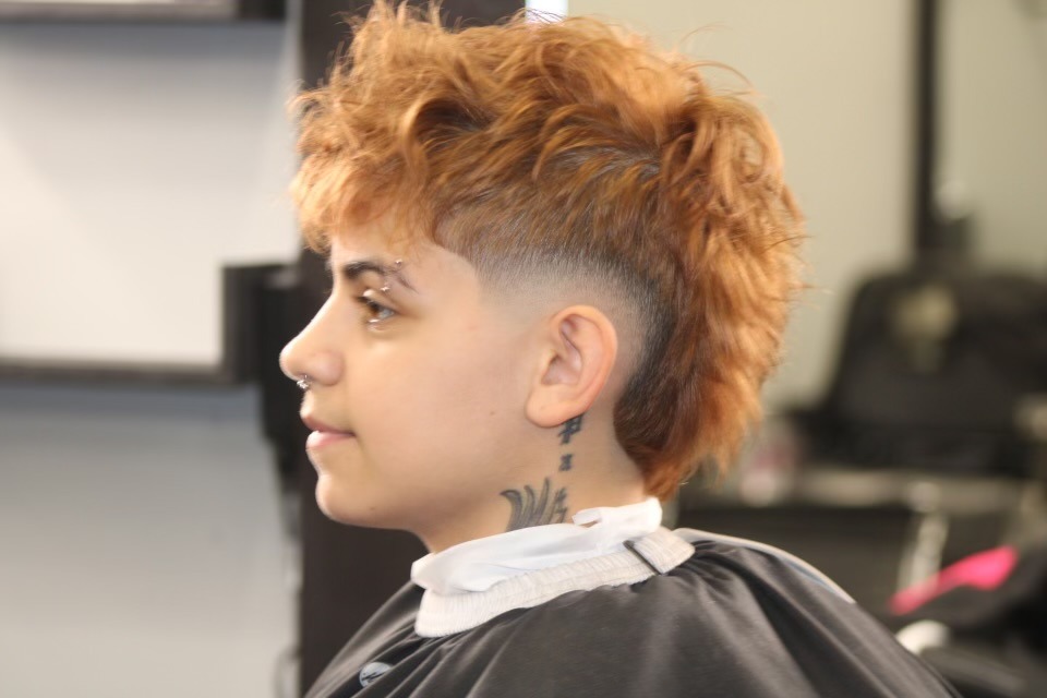 A young woman with vibrant red hair is seated in a salon.